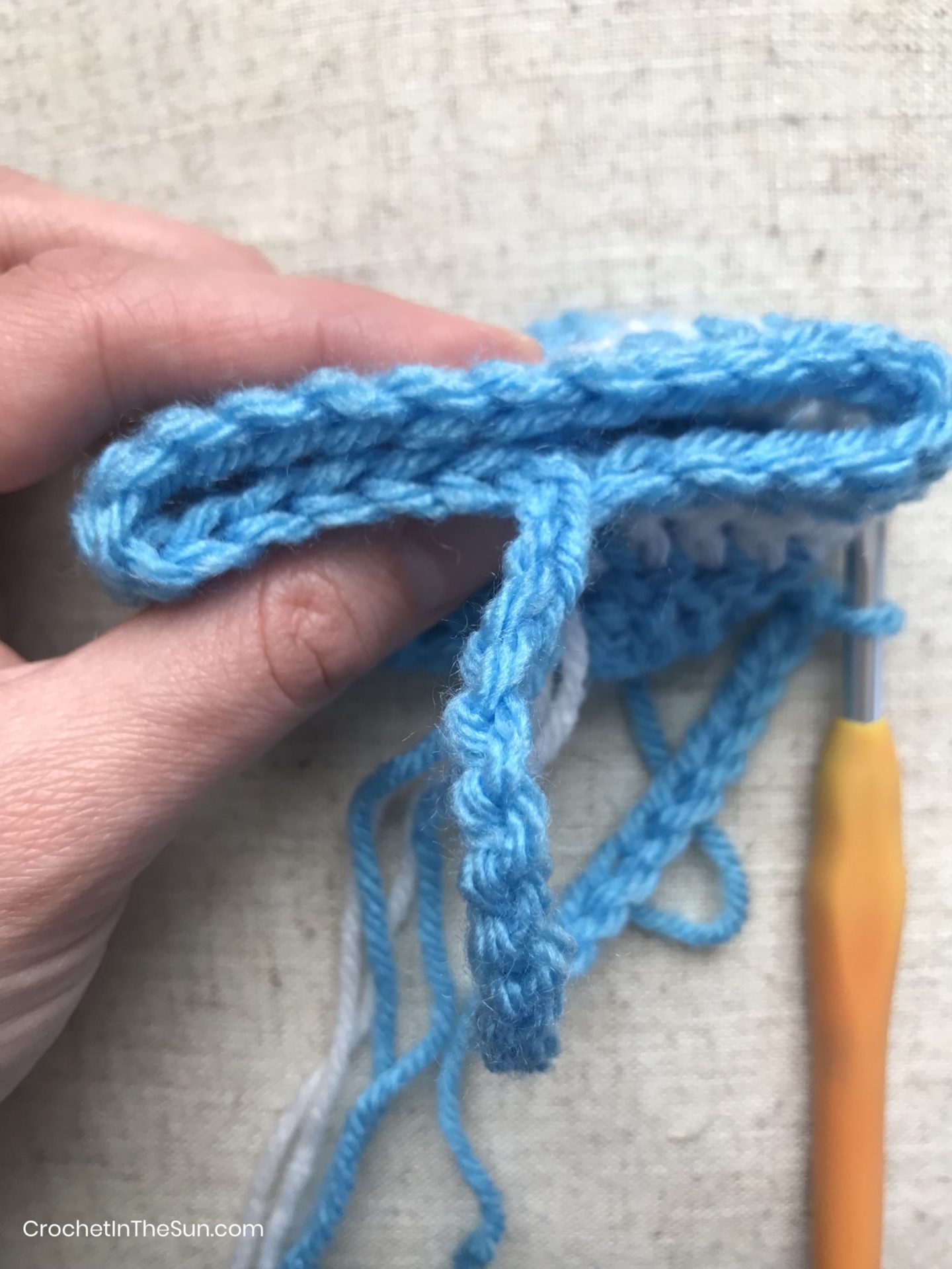 How to attach the handle to the crochet basket: Fold together and align the top stitches. This will help you see where to slip stitch to attach the handle.. #crochet #crochetinthesun #howtocrochet #crochettutorial #crochetforbeginners