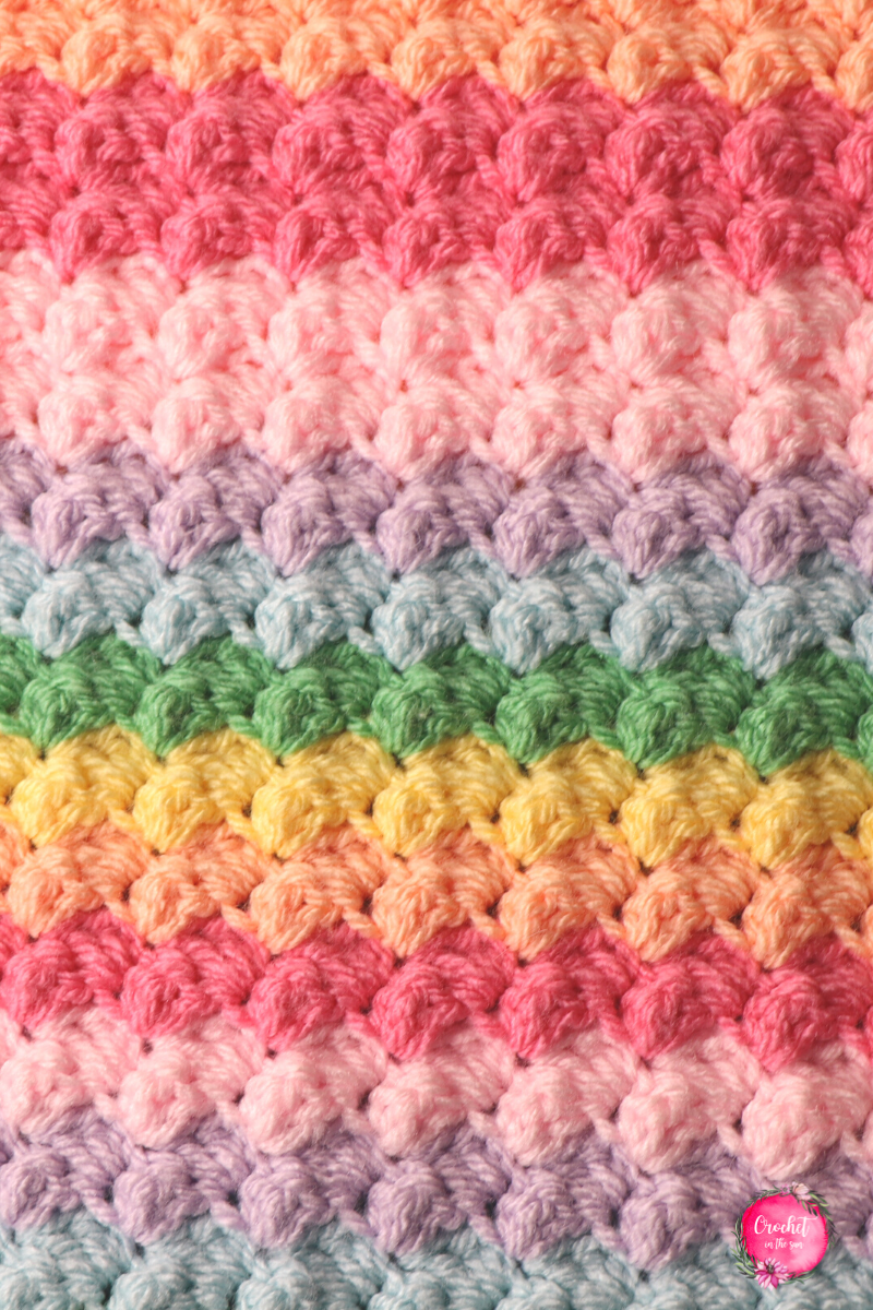 Here you can see the beautiful texture and pattern of this FREE Rainbow crochet blanket pattern. This is easy, quick to work up, and beginner friendly.