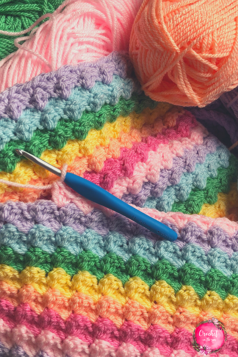 Crochet blanket - work in progress shot. This is a free and easy crochet blanket project full of colors. This rainbow crochet project is great for beginners, and works up to be a beautiful blanket with a great texture