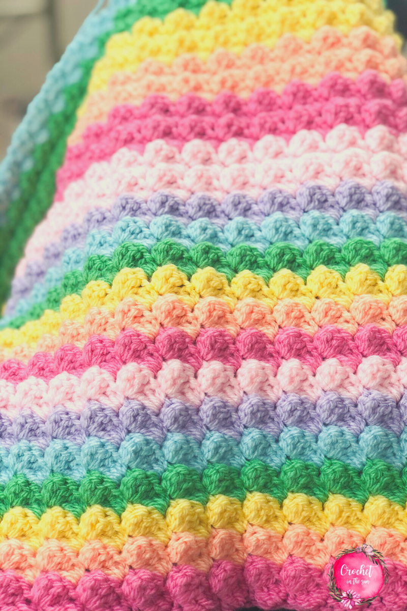 Free and easy rainbow crochet blanket pattern. This crochet project is perfect for beginners. The blanket is super cuddly and has a lovely texture.