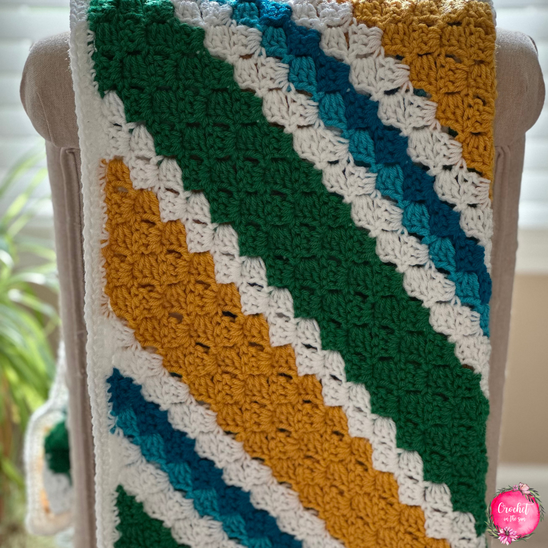Custom team crochet blanket draped on chair, corner-to-corner pattern for cozy sports nights.