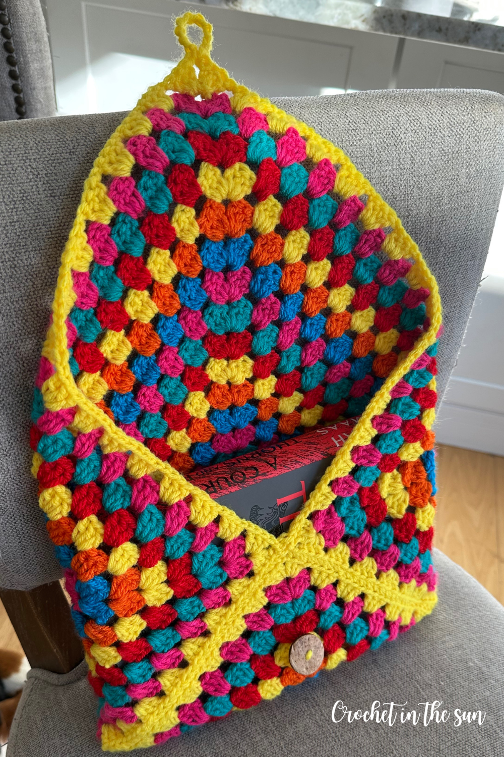 Colorful and stunning photo of the crochet book sleeve, with a book tucked into the sleeve! Functional and gorgeous!
